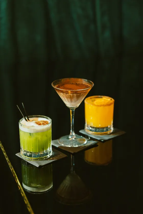 Three cocktails on a dark bar